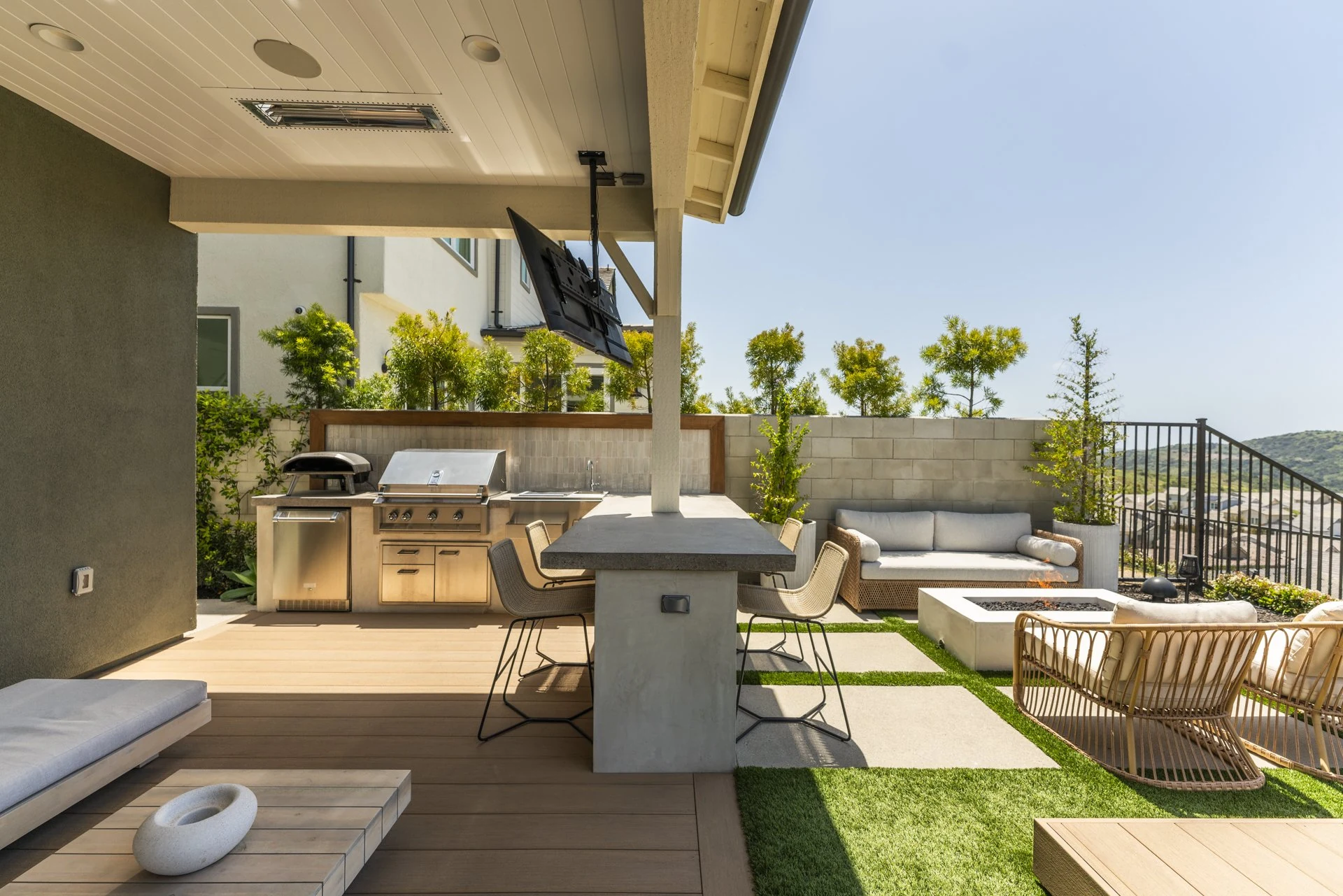 Covered outdoor kitchen with grill, pizza oven and bar counter.