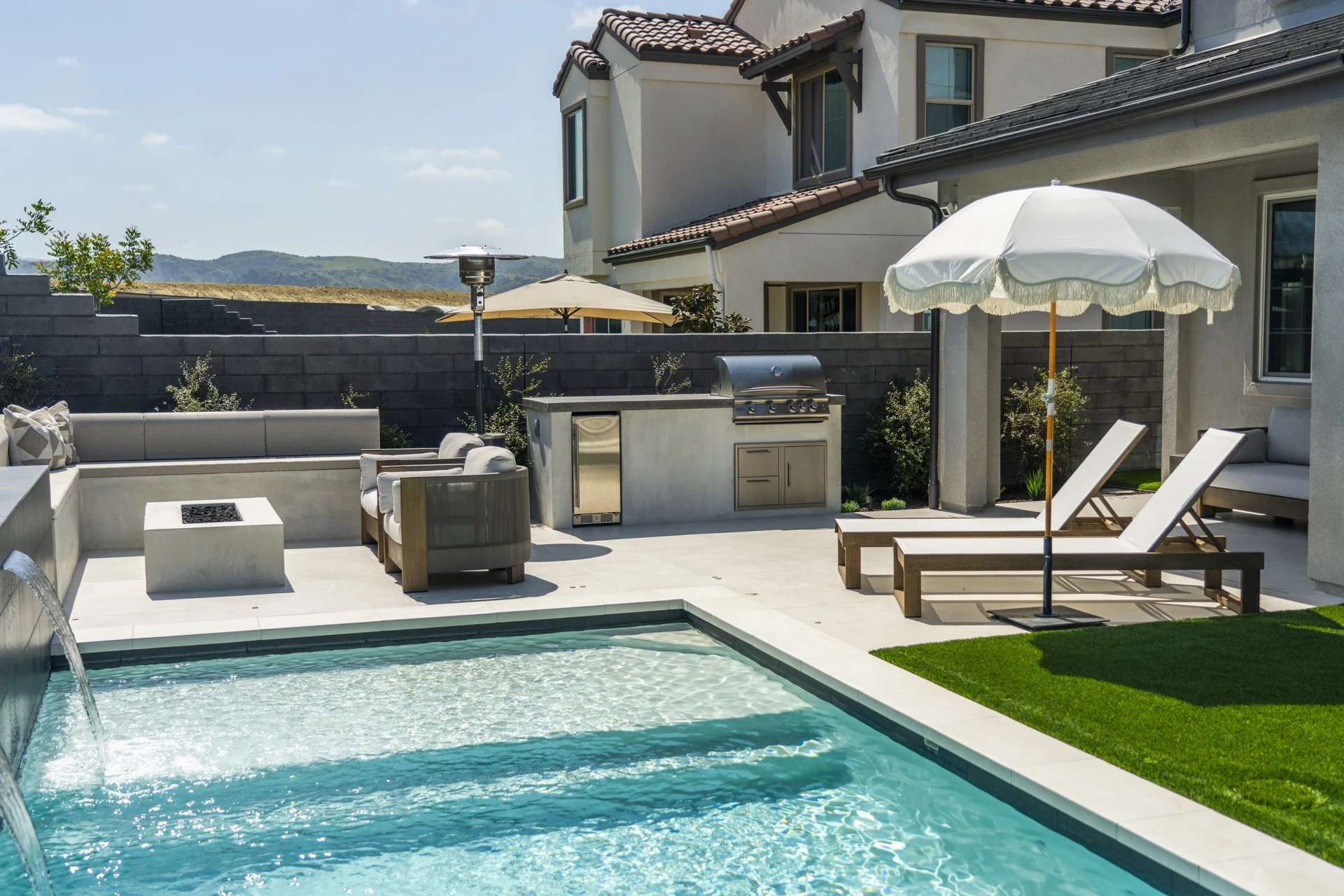 Pool with sheer descents, built-in lounge, BBQ island and chaises.