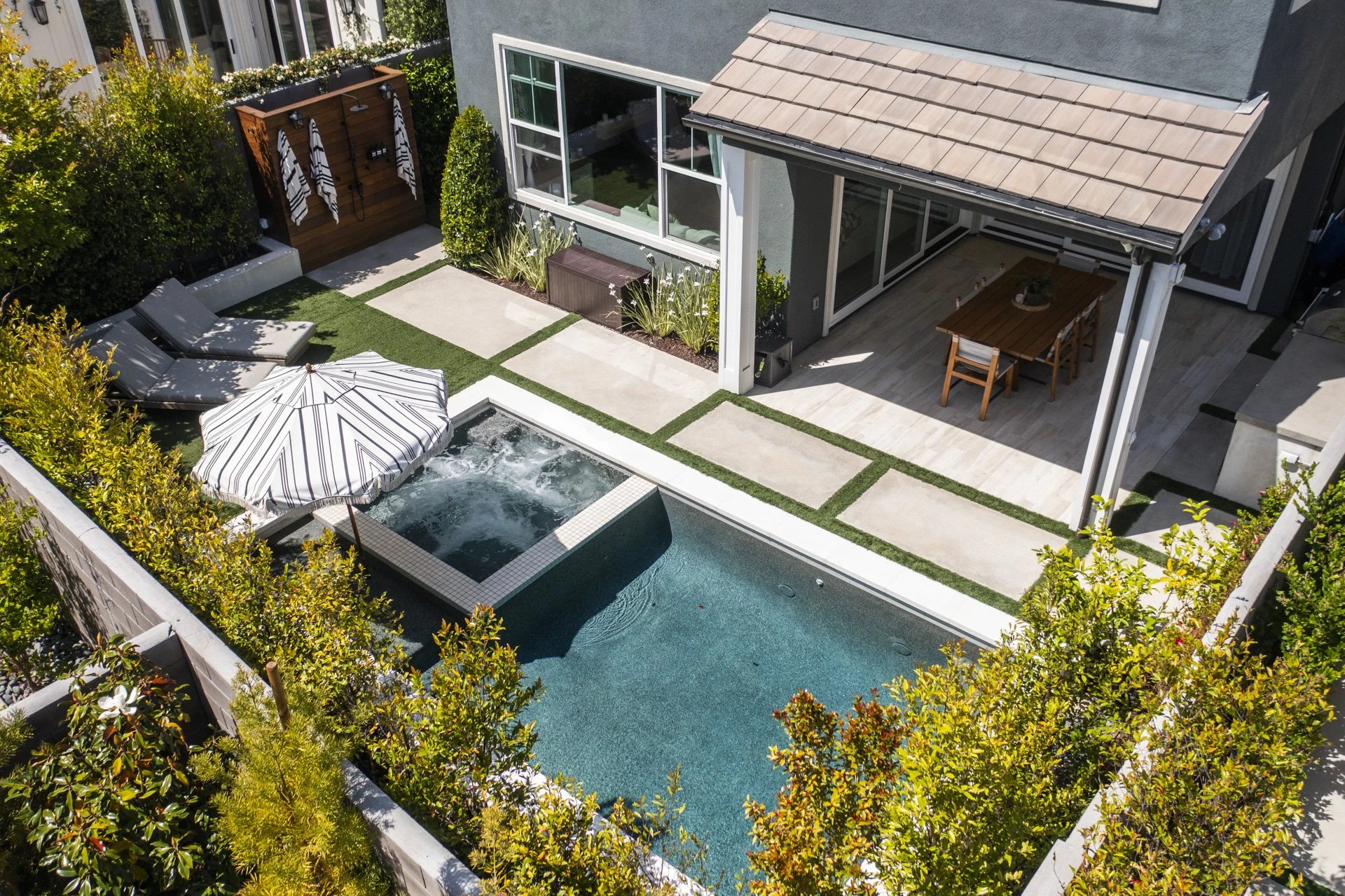 Aerial view of a covered patio, pool and spa with concrete pads in turf.