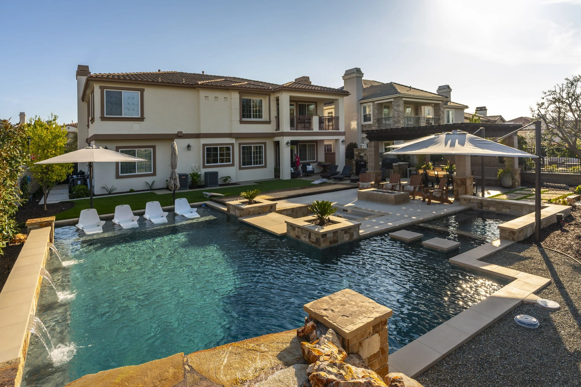 Pool with tanning ledge, in-pool loungers and a stone planter island.